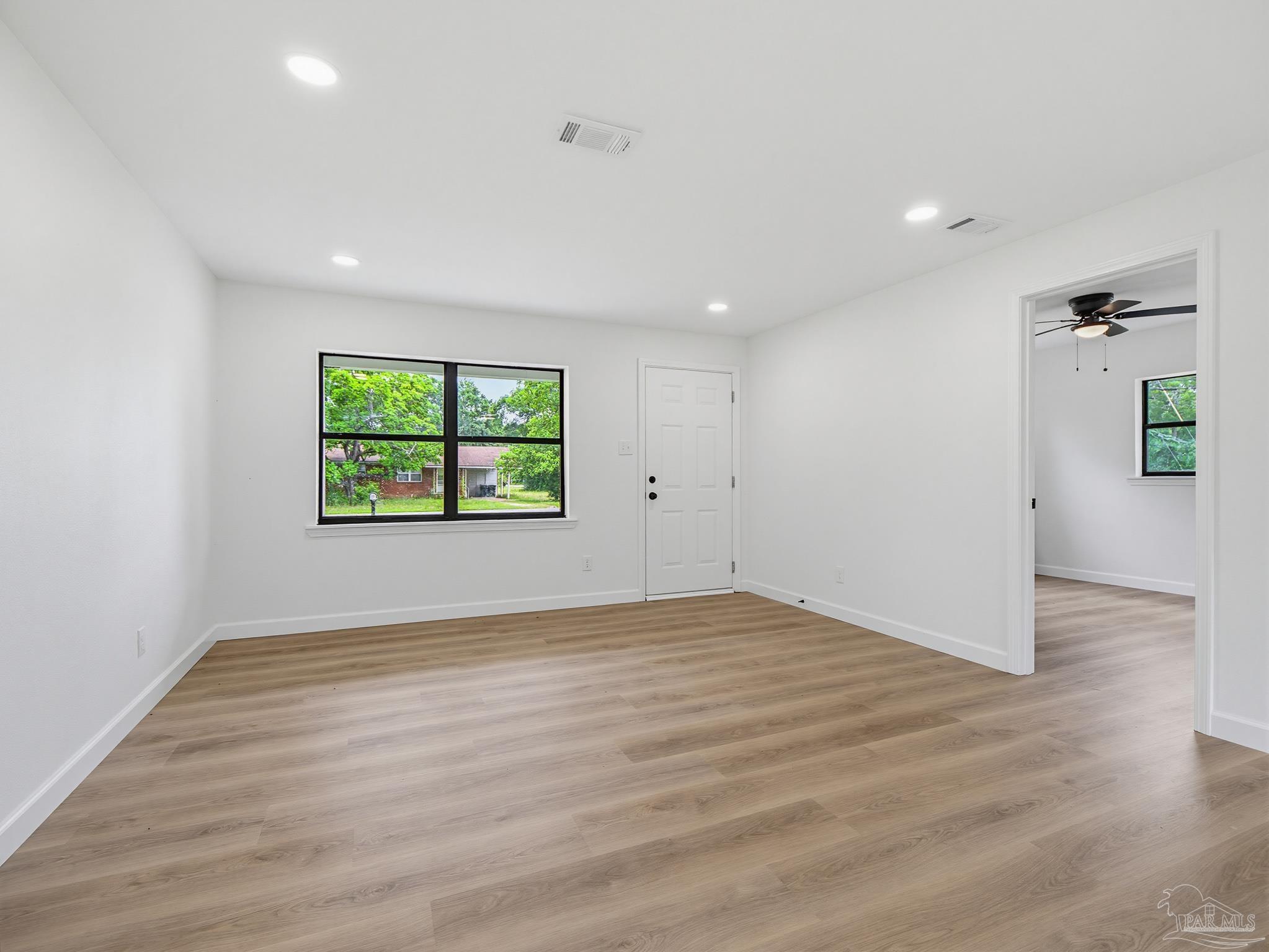 125 Madrid Road Cantonment, FL 32533 - Photo 3 of 16 an empty room with wooden floor and windows