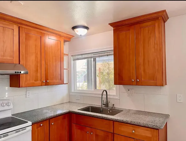 a kitchen with granite countertop a sink window and cabinets
