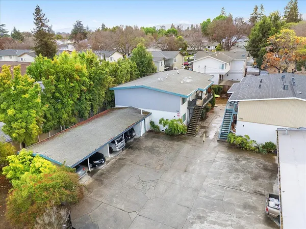an aerial view of a house with yard and trees in the background
