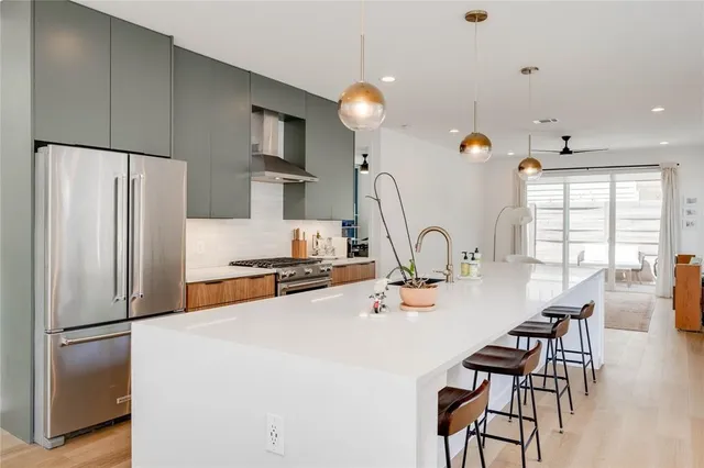 a kitchen with stainless steel appliances granite countertop a stove top oven a sink dishwasher a dining table and chairs with wooden floor