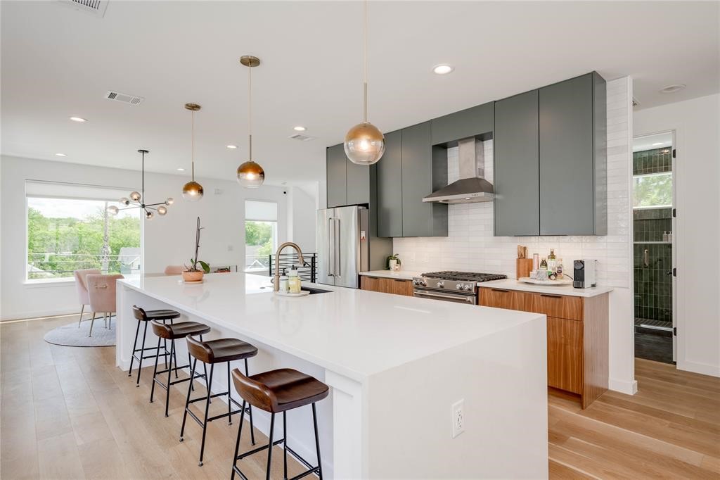 1208 Luna Street, Unit 1 Austin, TX 78721 - Photo 6 of 39 a kitchen with stainless steel appliances granite countertop a stove top oven a sink dishwasher a dining table and chairs with wooden floor
