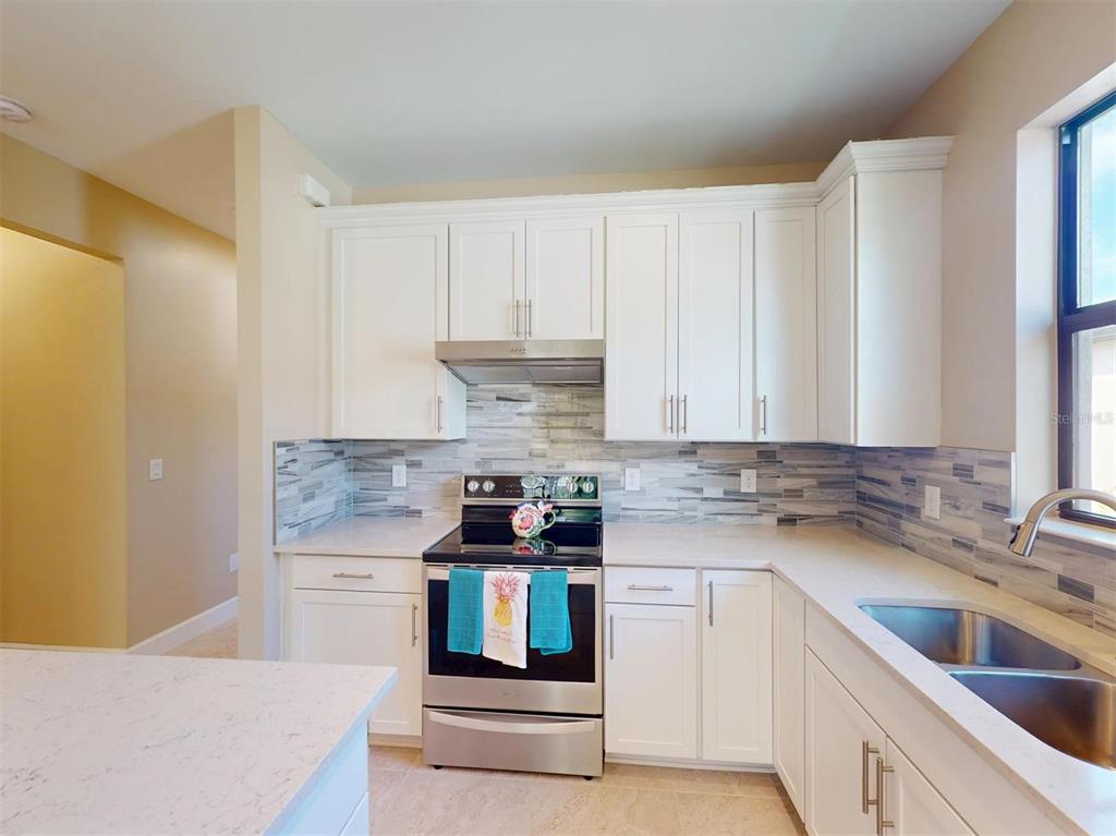 1352 Raspberry Dr Port North Port, FL 34289 - Photo 19 of 88 a kitchen with stainless steel appliances granite countertop a sink stove and cabinets