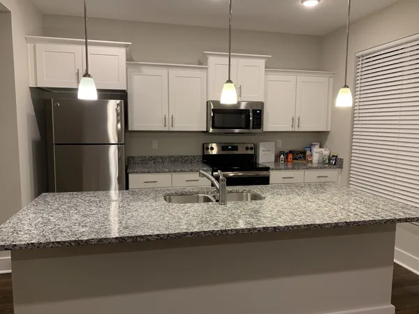 a kitchen with stainless steel appliances granite countertop a sink a refrigerator a microwave a sink and a counter