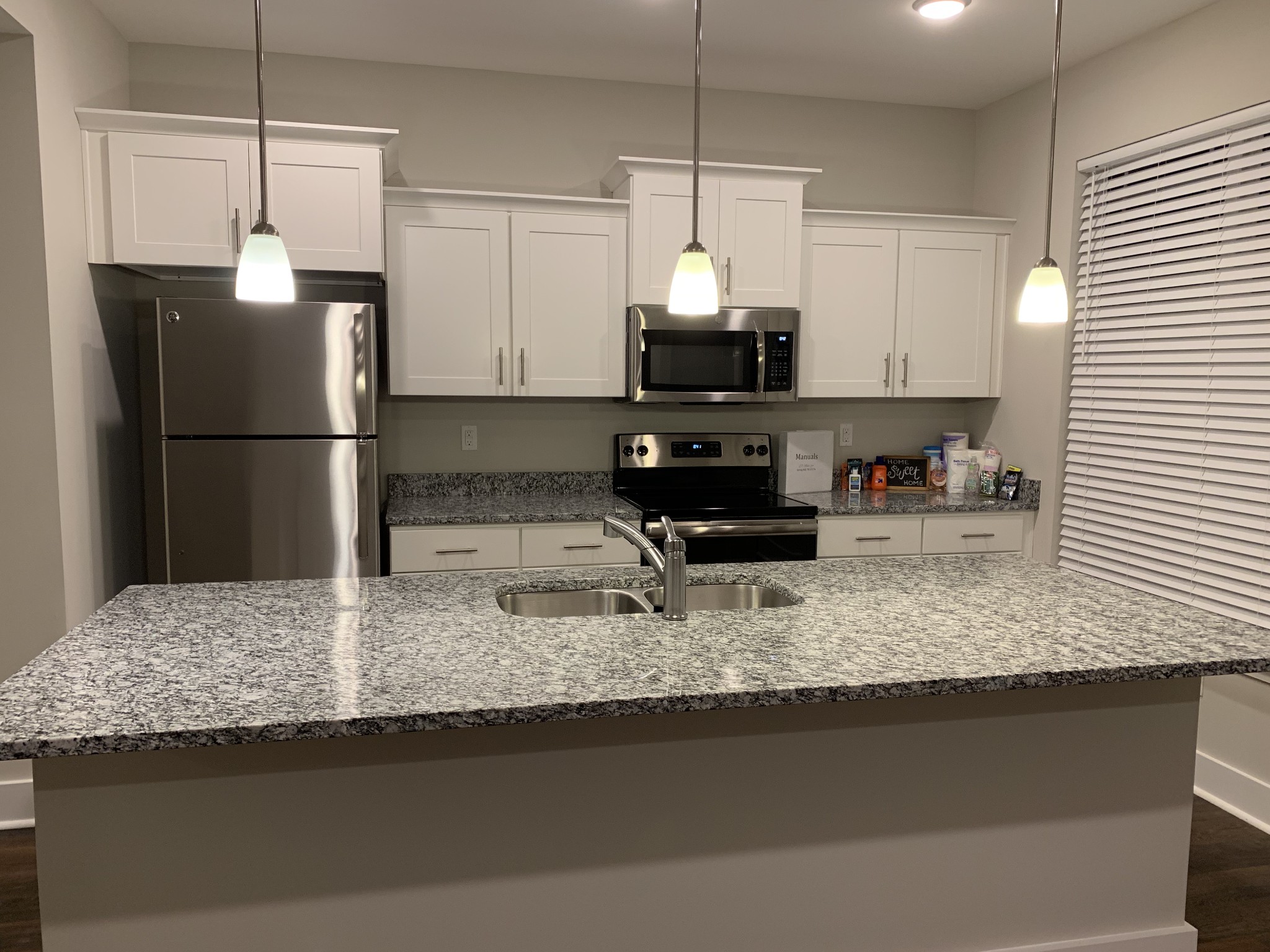 a kitchen with stainless steel appliances granite countertop a sink a refrigerator a microwave a sink and a counter