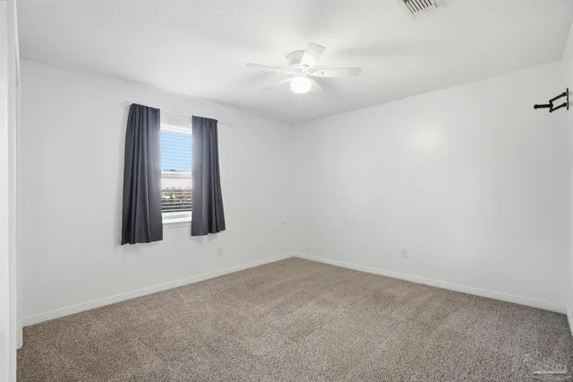 an empty room with windows and fan