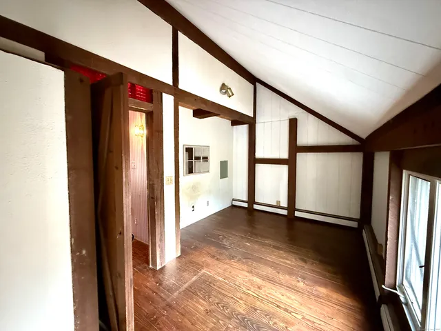 an empty room with wooden floor and windows with curtains