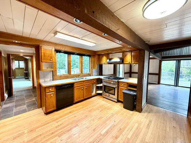a large kitchen with stainless steel appliances granite countertop a large counter top oven a sink dishwasher a dining table and chairs with wooden floor