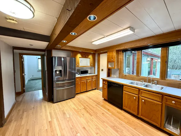 a large kitchen with stainless steel appliances wooden cabinets a oven and a large window