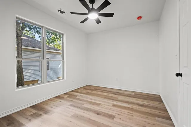 a view of an empty room with a window and ceiling fan