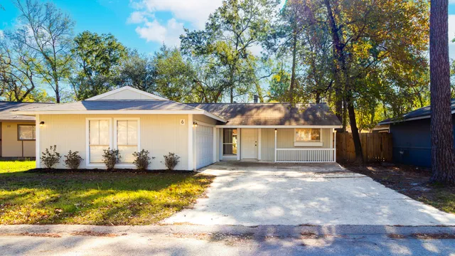 a front view of a house with a yard and large trees