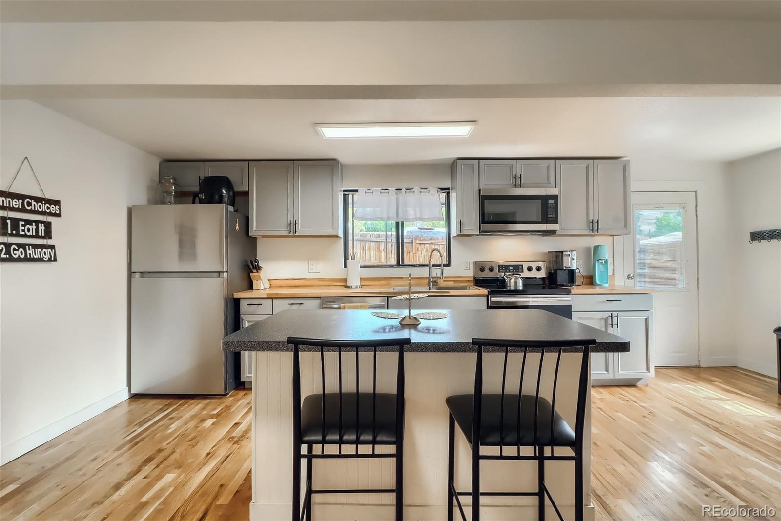 4175 West Custer Place Denver, CO 80219 - Photo 14 of 38 a kitchen with stainless steel appliances granite countertop a refrigerator a stove a sink a dining table and chairs with wooden floor
