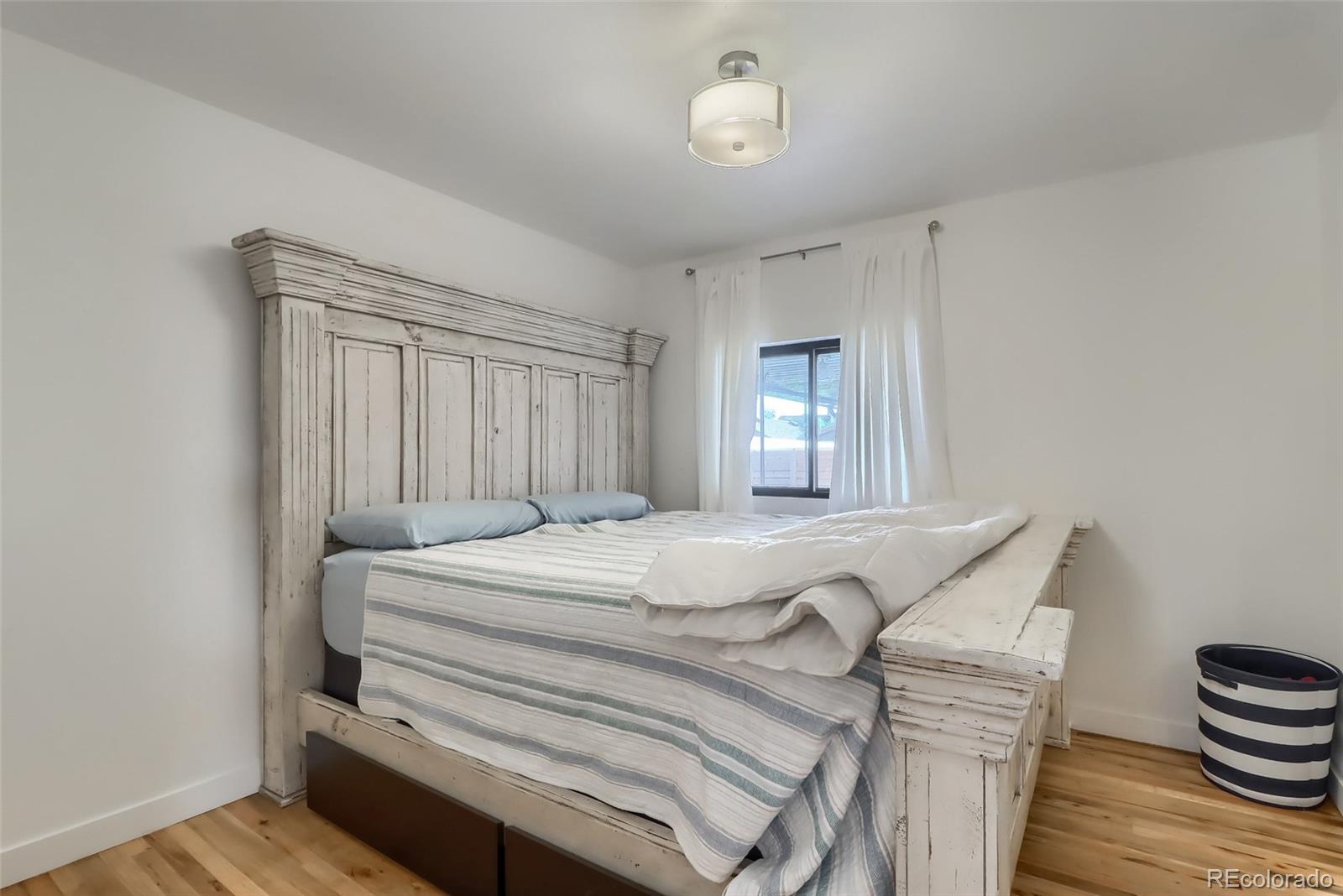4175 West Custer Place Denver, CO 80219 - Photo 22 of 38 a spacious bedroom with a bed and a chandelier