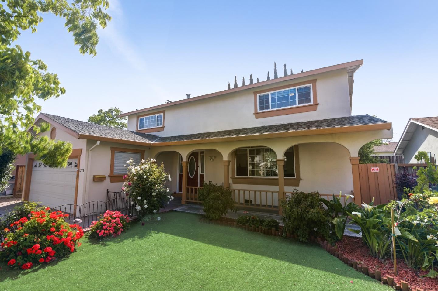 a front view of house and yard with beautiful flowers and green space