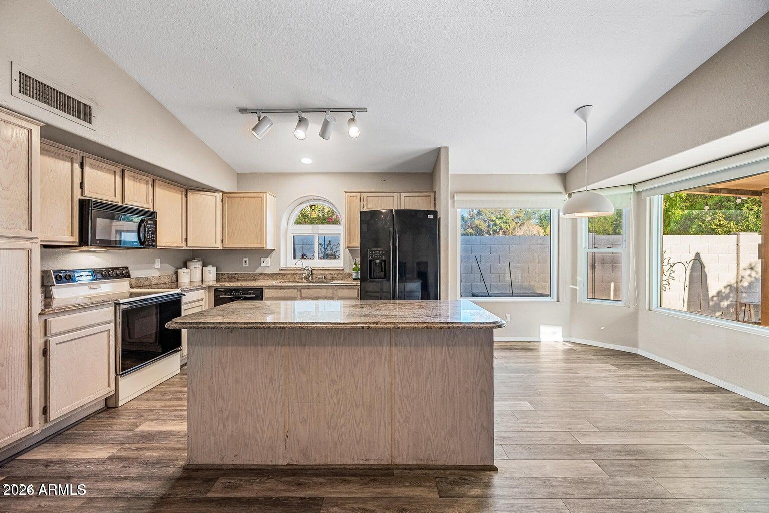 473 West Smoke Tree Road Gilbert, AZ 85233 - Photo 13 of 43 a view of kitchen with kitchen island granite countertop a stove top oven a sink dishwasher a dining table and chairs with wooden floor