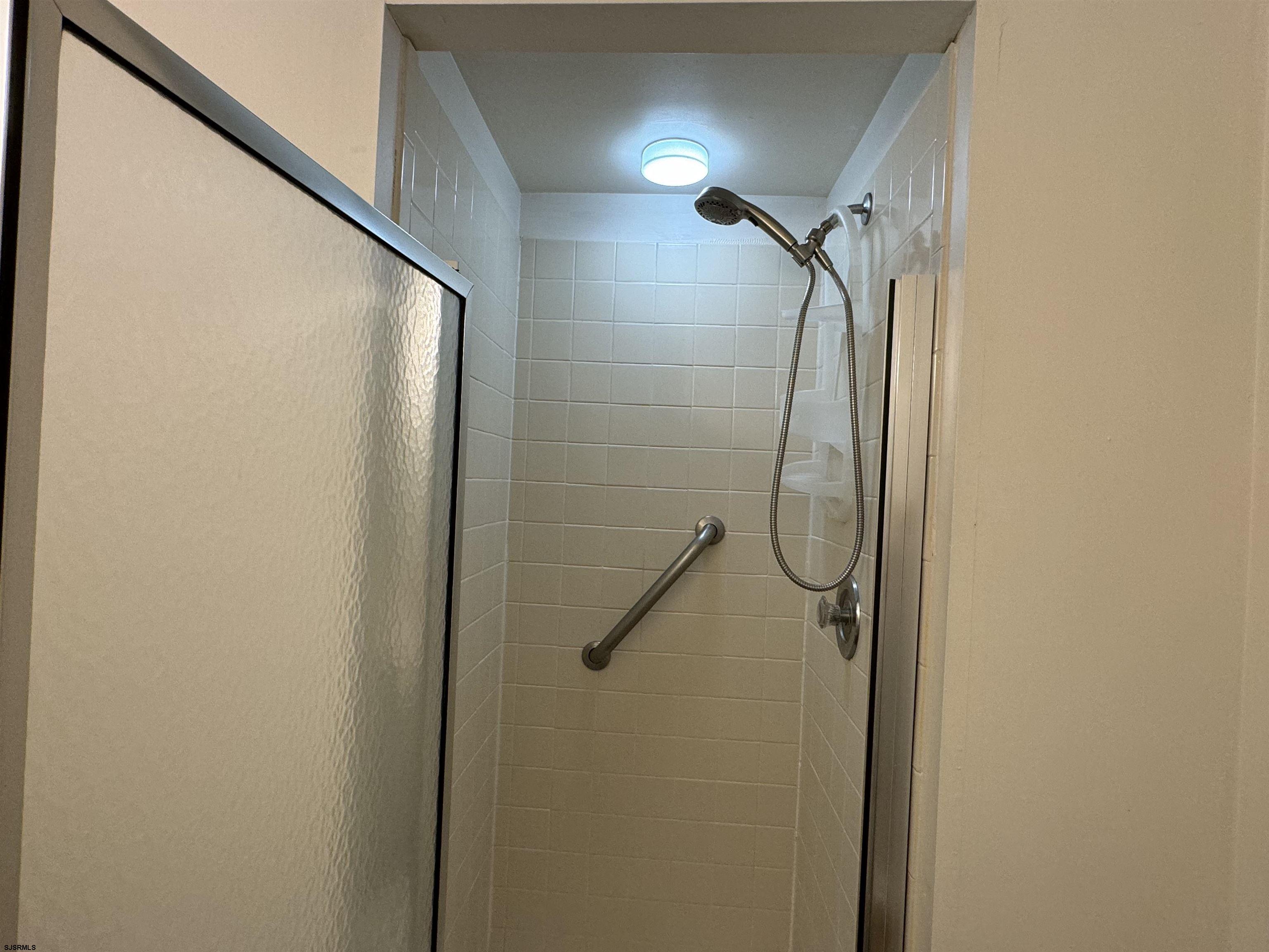 407 36th Street South, Unit 2 Brigantine, NJ 08203 - Photo 14 of 30 a bathroom with a glass shower door and mirror