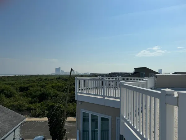 a view of a roof deck with couches and wooden fence