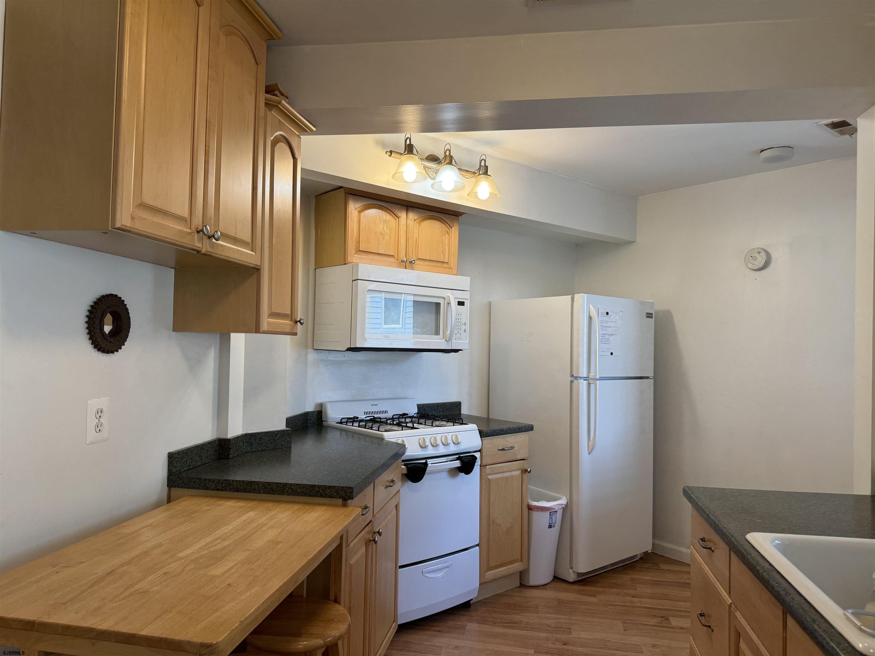407 36th Street South, Unit 2 Brigantine, NJ 08203 - Photo 9 of 30 a kitchen with stainless steel appliances granite countertop a refrigerator a sink dishwasher a stove with wooden cabinets
