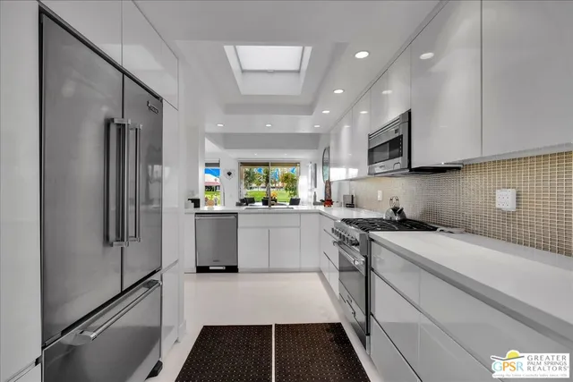 a kitchen with a refrigerator a sink and white cabinets