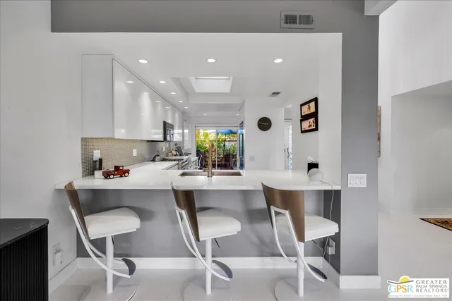 a kitchen with white cabinets and chairs