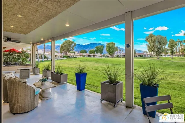 a living room with patio furniture and a garden