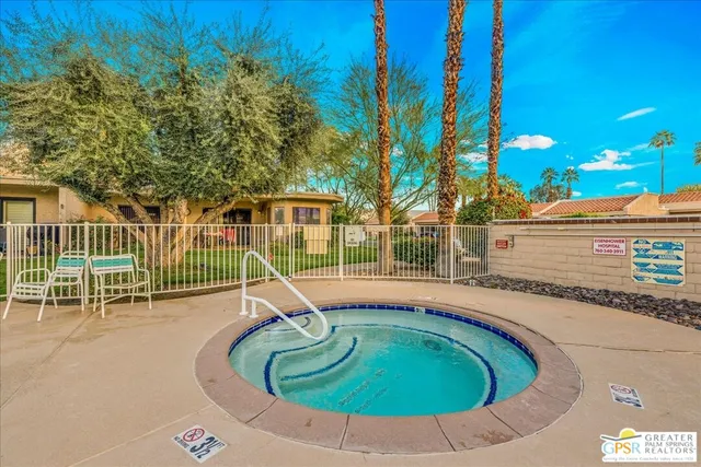 a small pool with lawn chairs and wooden fence