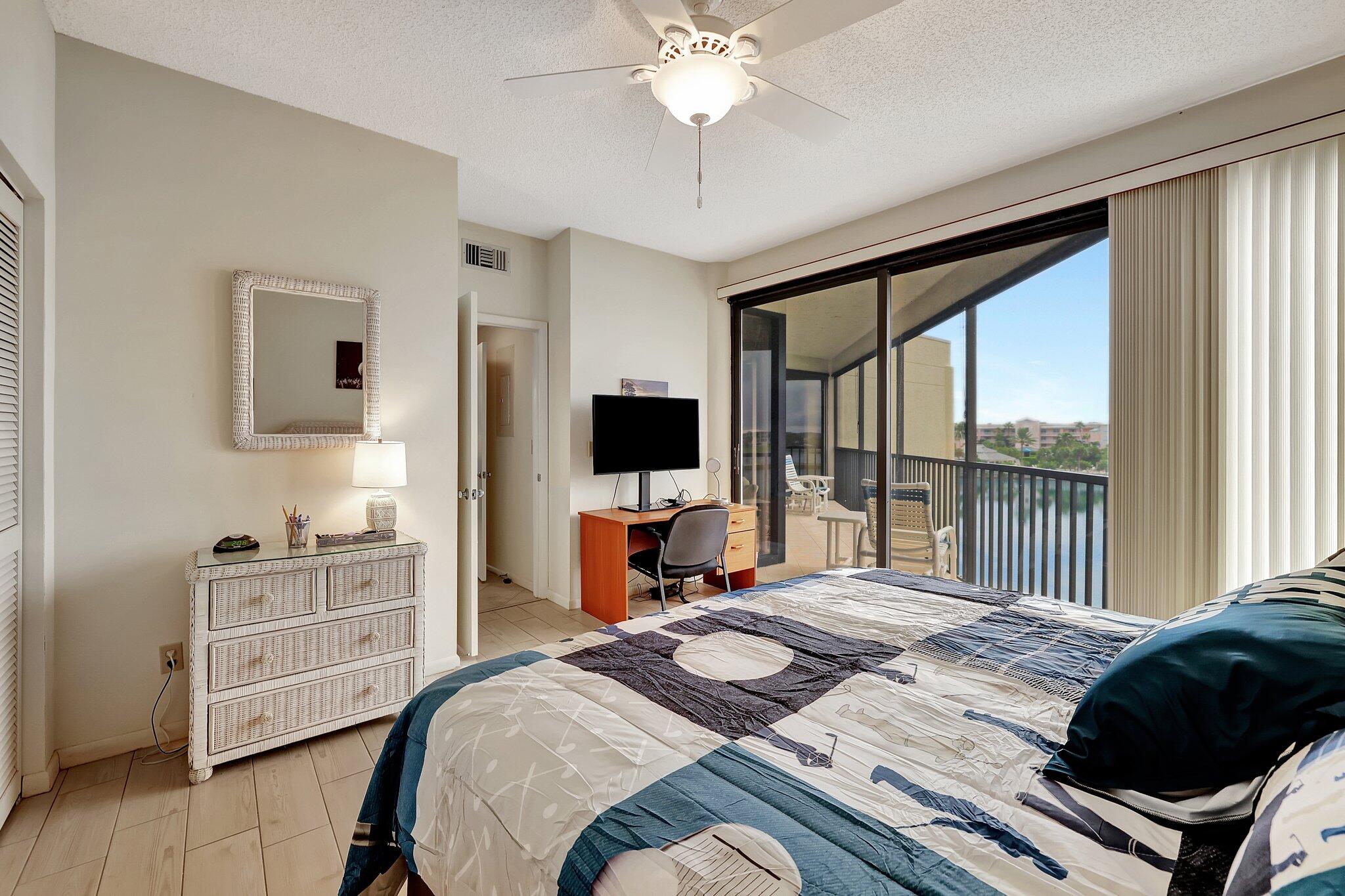 221 Northeast Plantation Road, Unit 406 Stuart, FL 34996 - Photo 19 of 58 a bedroom with a bed a flat screen tv and a fireplace