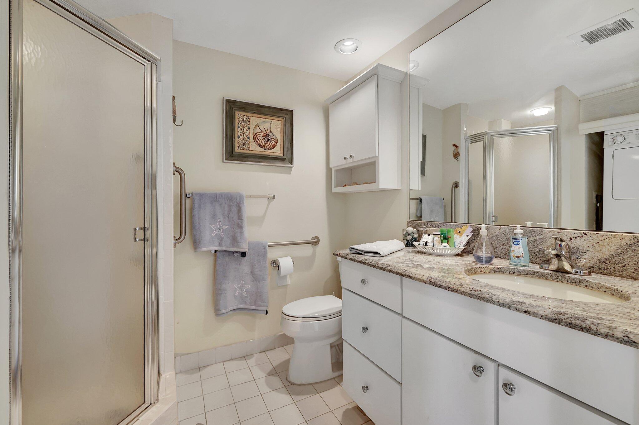 221 Northeast Plantation Road, Unit 406 Stuart, FL 34996 - Photo 22 of 58 a bathroom with a granite countertop sink a toilet and a mirror