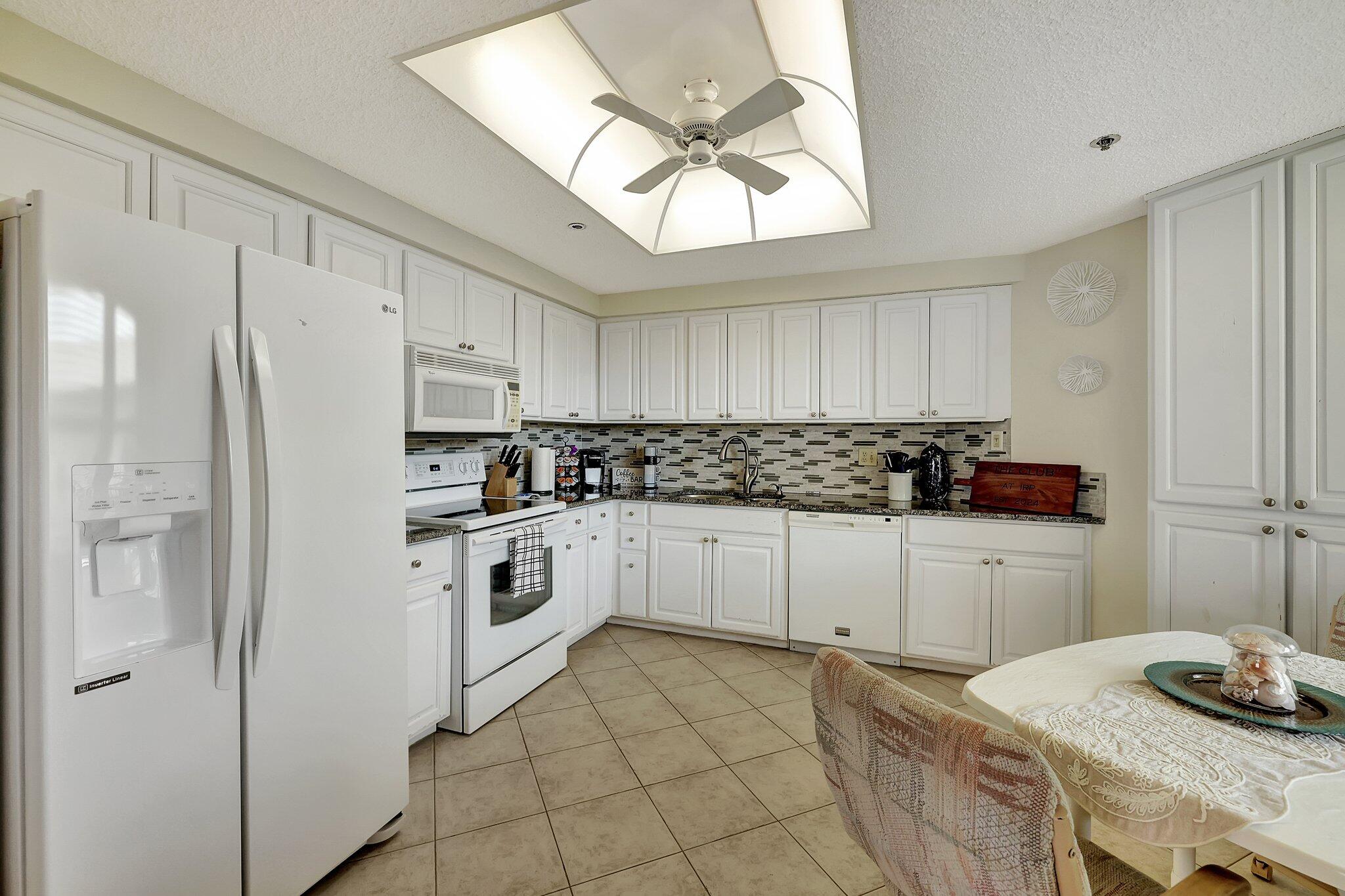 221 Northeast Plantation Road, Unit 406 Stuart, FL 34996 - Photo 9 of 58 a kitchen with stainless steel appliances a stove a sink and white cabinets