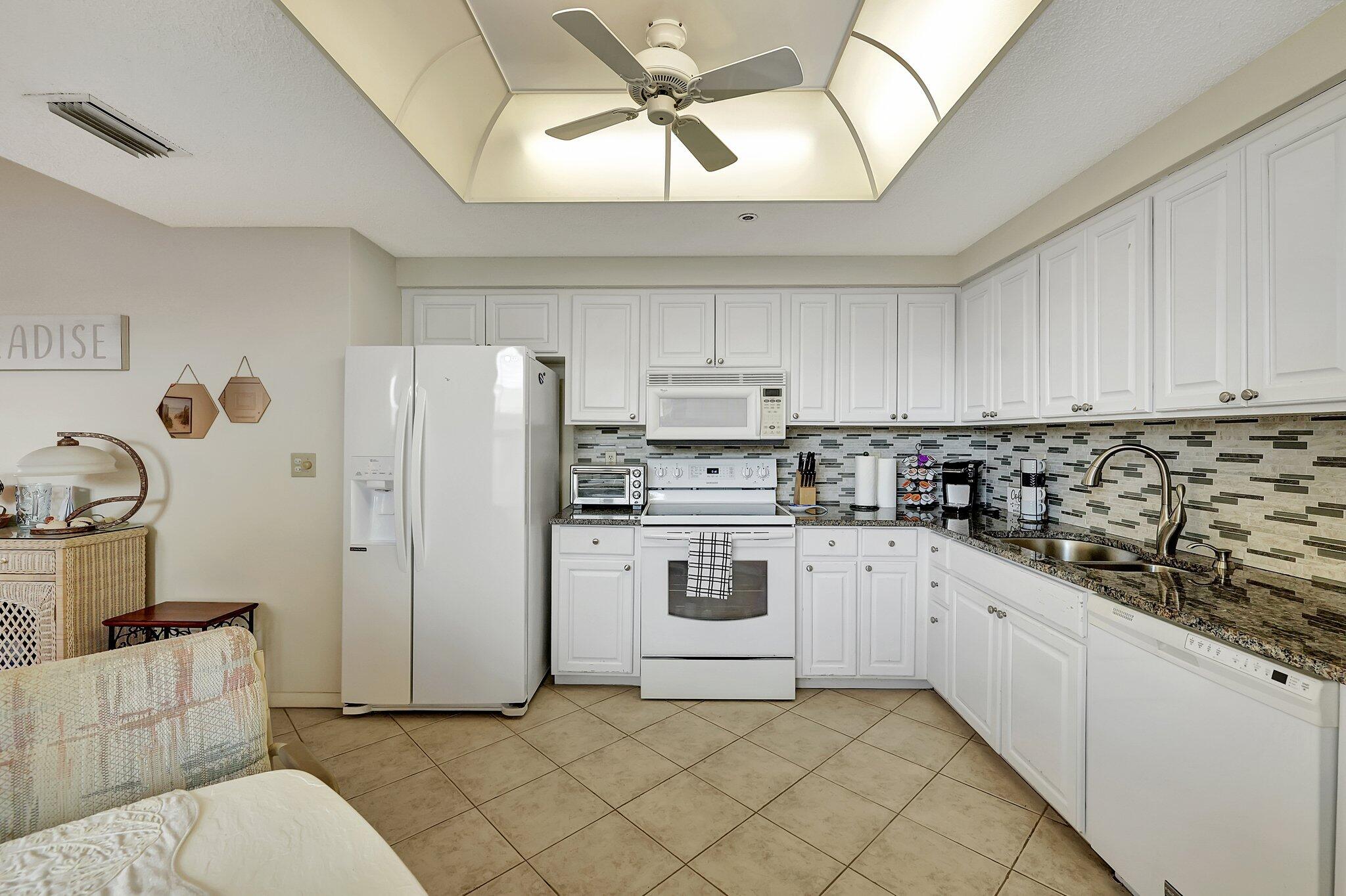 221 Northeast Plantation Road, Unit 406 Stuart, FL 34996 - Photo 10 of 58 a kitchen with a refrigerator and white cabinets