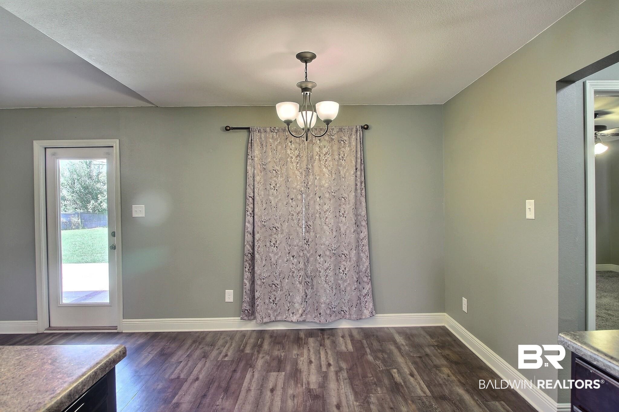 15577 Talus Court Foley, AL 36535 - Photo 9 of 28 Unfurnished dining area featuring dark wood-style flooring and a chandelier