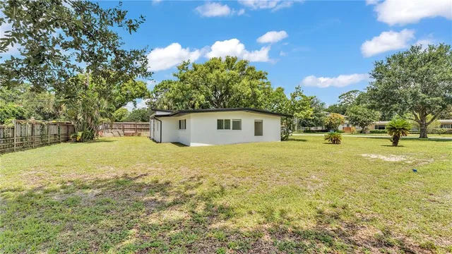 a view of a house with a yard and a large tree