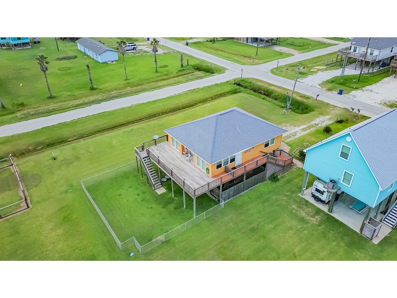 419 Thunder Road Surfside Beach, TX 77541 - Photo 30 of 32 This aerial view showcases a charming elevated home with a spacious wooden deck and fenced yard, located on a corner lot in a quiet neighborhood. Ideal for enjoying outdoor activities and scenic views.