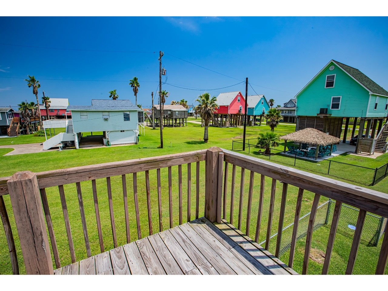419 Thunder Road Surfside Beach, TX 77541 - Photo 7 of 32 This charming home offers a vibrant view of colorful, elevated beach houses and lush green lawns, perfect for coastal living.