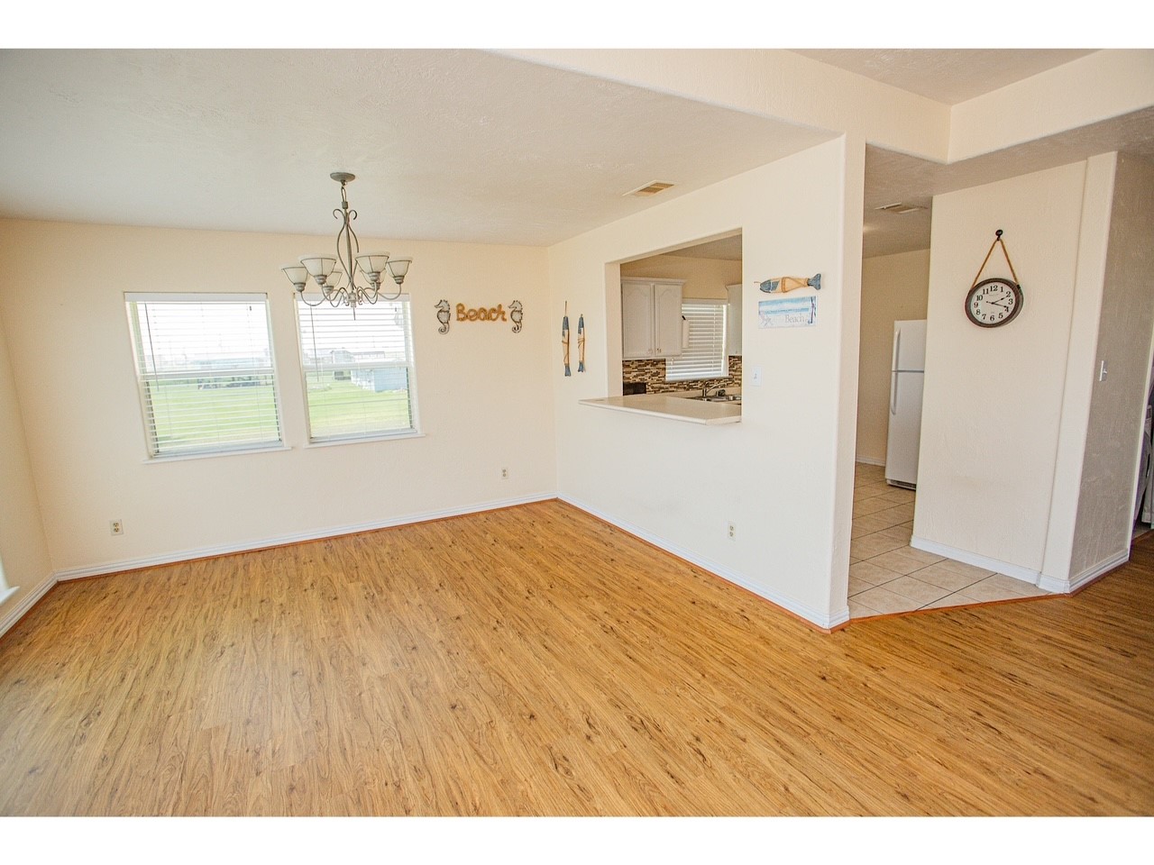 419 Thunder Road Surfside Beach, TX 77541 - Photo 10 of 32 Bright, open living space with wood flooring and a chandelier. Features a pass-through to the kitchen with tile flooring. Large windows offer plenty of natural light.