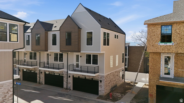 7338 South Seven Tree Lane, Unit 75 Midvale, UT 84047 - Photo 25 of 30 Contemporary home featuring a garage, stone siding, driveway, and a balcony