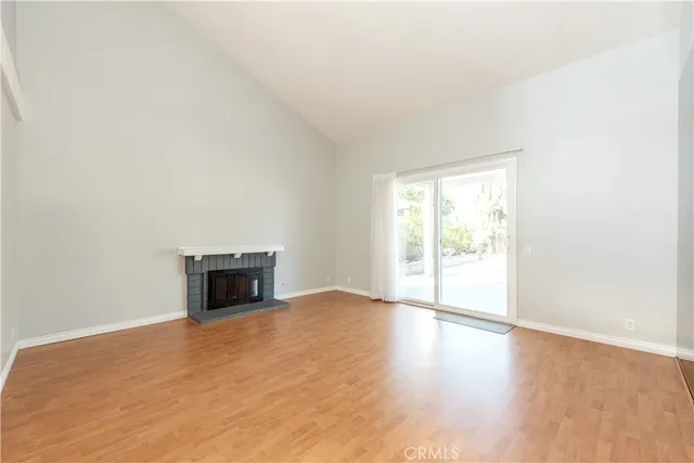 a view of empty room with wooden floor and fireplace