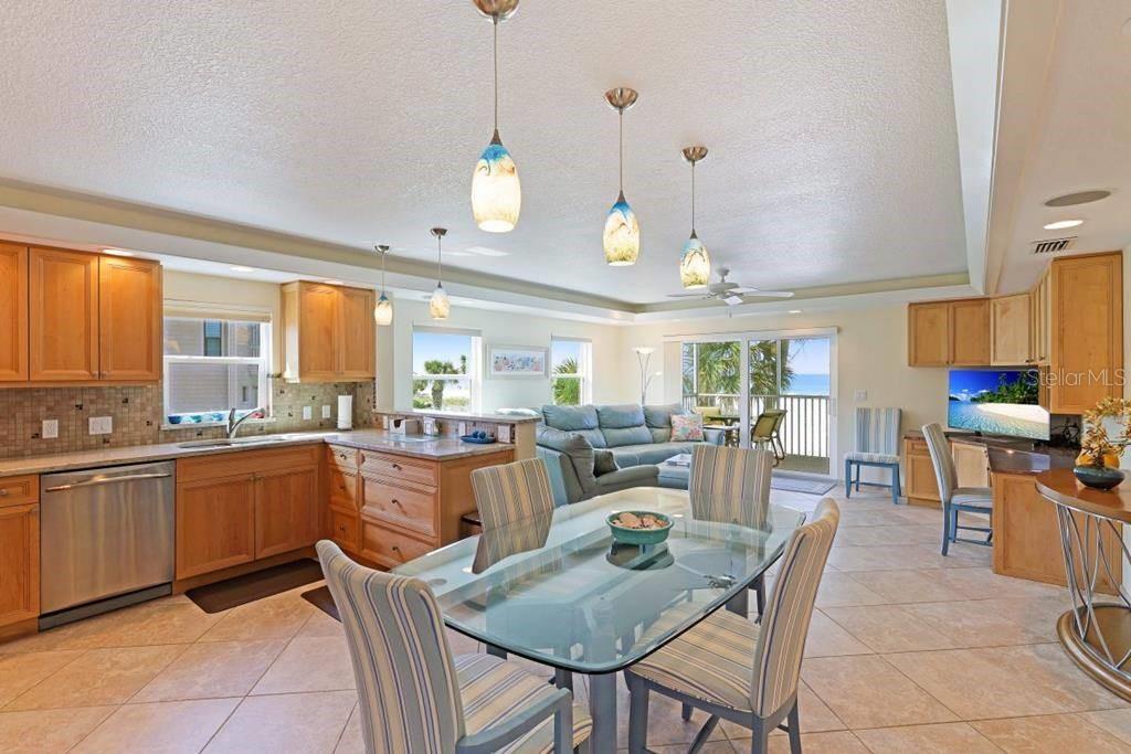 6154 Midnight Pass Road, Unit 201 Sarasota, FL 34242 - Photo 5 of 11 a kitchen with stainless steel appliances granite countertop a stove a sink a dining table and chairs with wooden floor