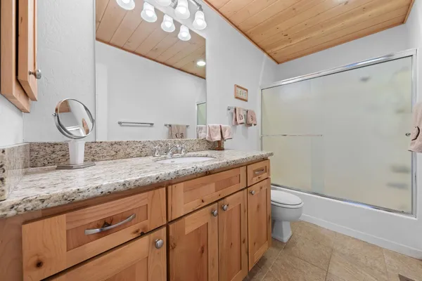 a bathroom with a granite countertop sink a toilet and a mirror