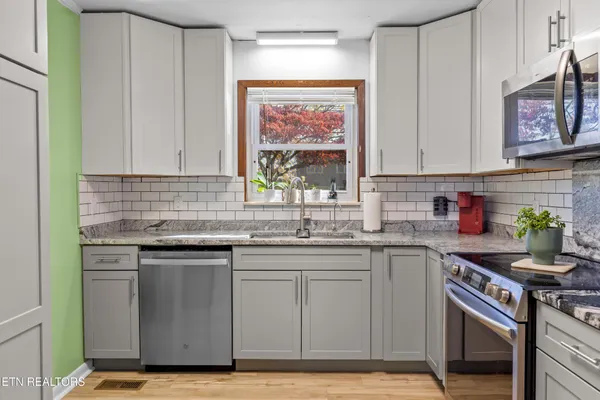 a kitchen with stainless steel appliances granite countertop a stove a sink and a microwave
