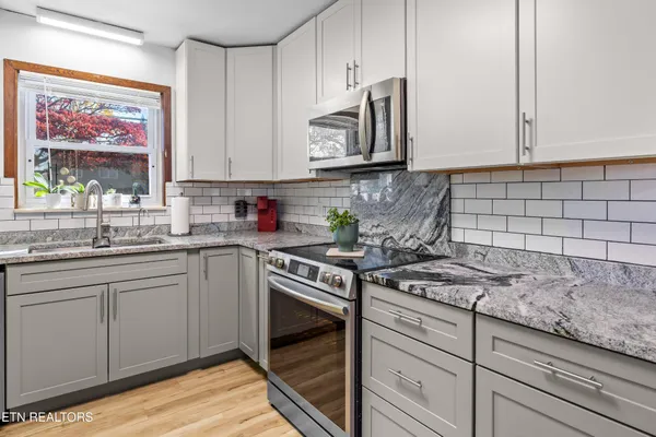 a kitchen with stainless steel appliances granite countertop white cabinets a stove and a sink