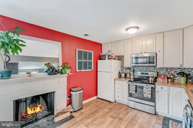 a kitchen with granite countertop a stove top oven a refrigerator a oven and a dining table with wooden floor