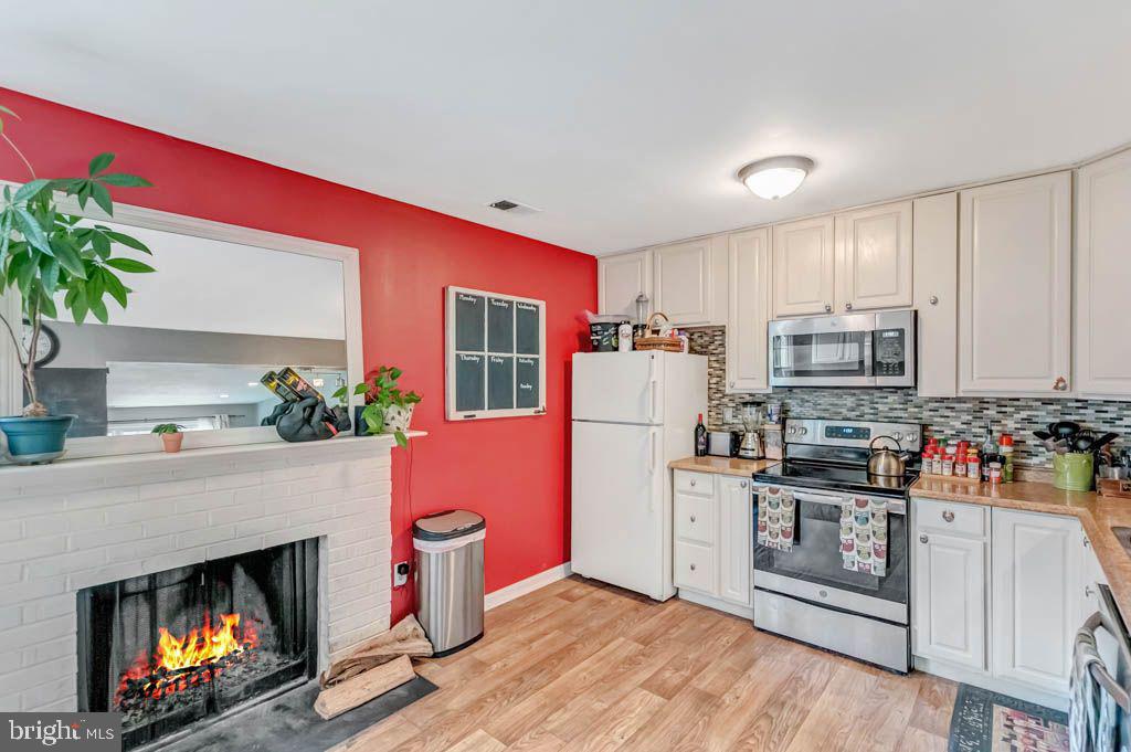 1677 Brice Court Crofton, MD 21114 - Photo 12 of 34 a kitchen with granite countertop a stove top oven a refrigerator a oven and a dining table with wooden floor