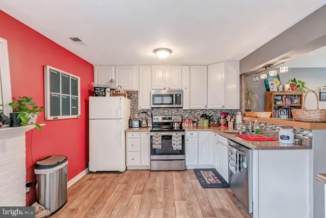 a kitchen with a refrigerator a stove a sink dishwasher and wooden cabinets with wooden floor