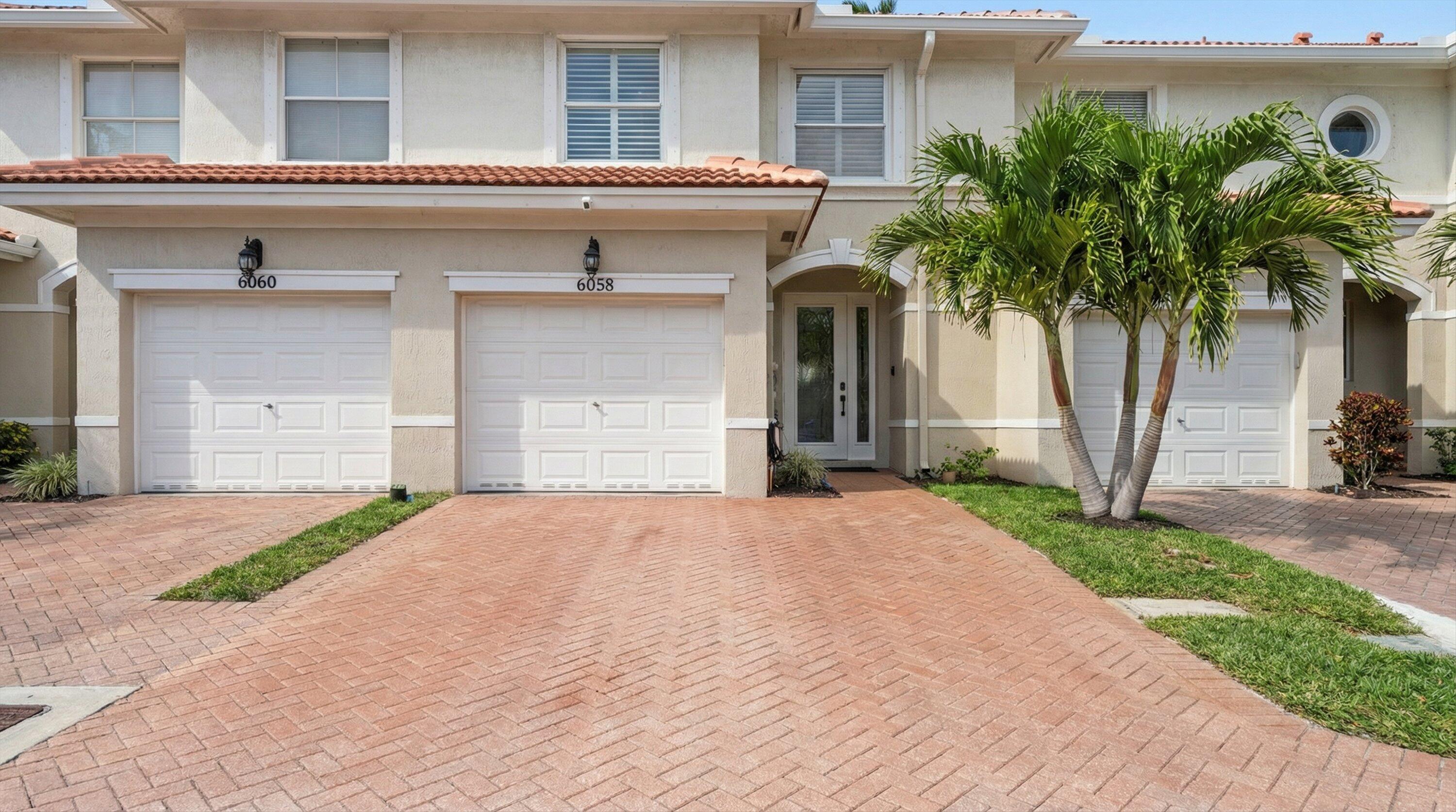6058 Seminole Gardens Circle Riviera Beach, FL 33418 - Photo 2 of 47 a front view of a house with a yard and garage