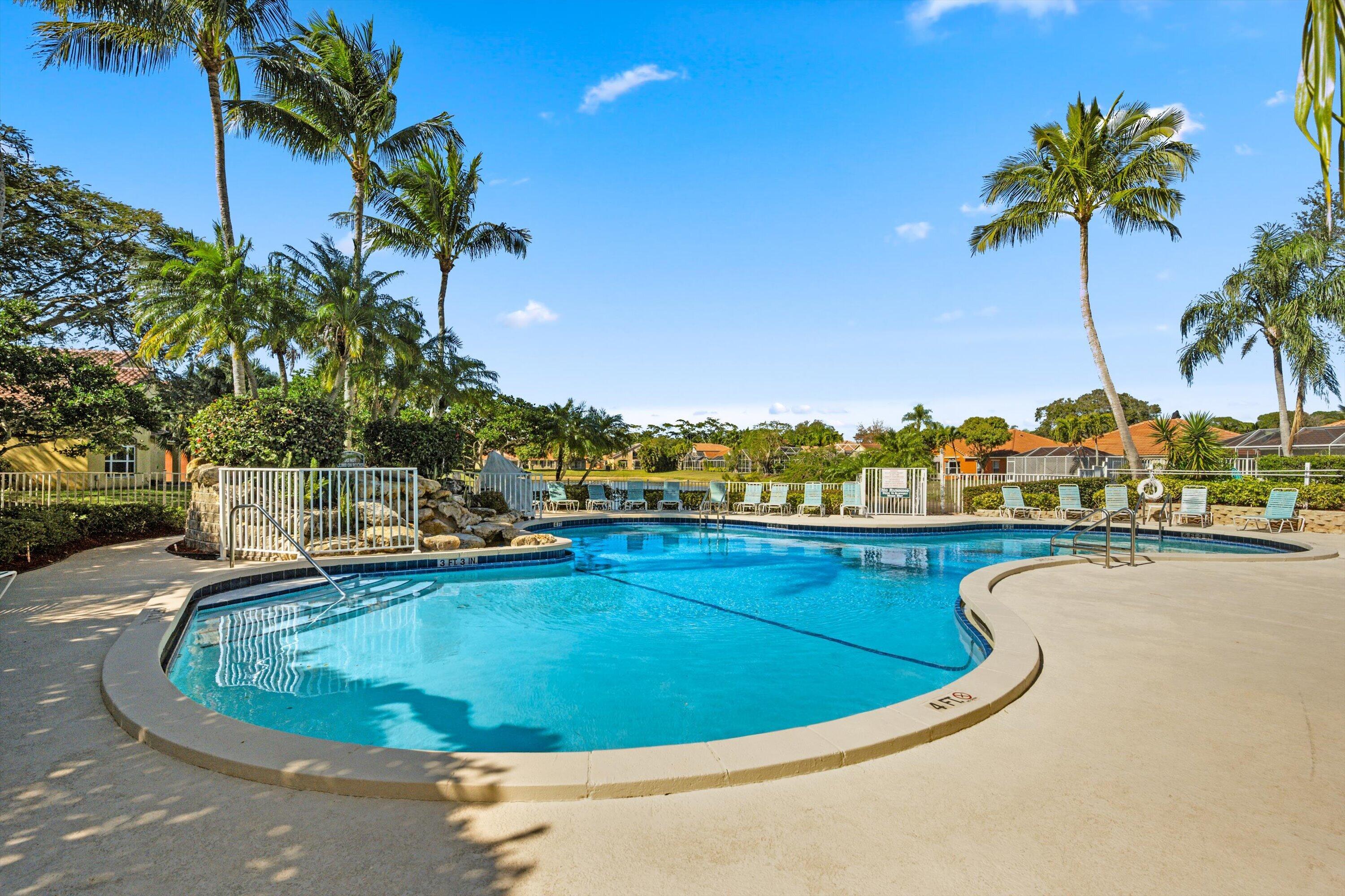 6058 Seminole Gardens Circle Riviera Beach, FL 33418 - Photo 34 of 47 a view of a swimming pool with a lawn chairs under an umbrella
