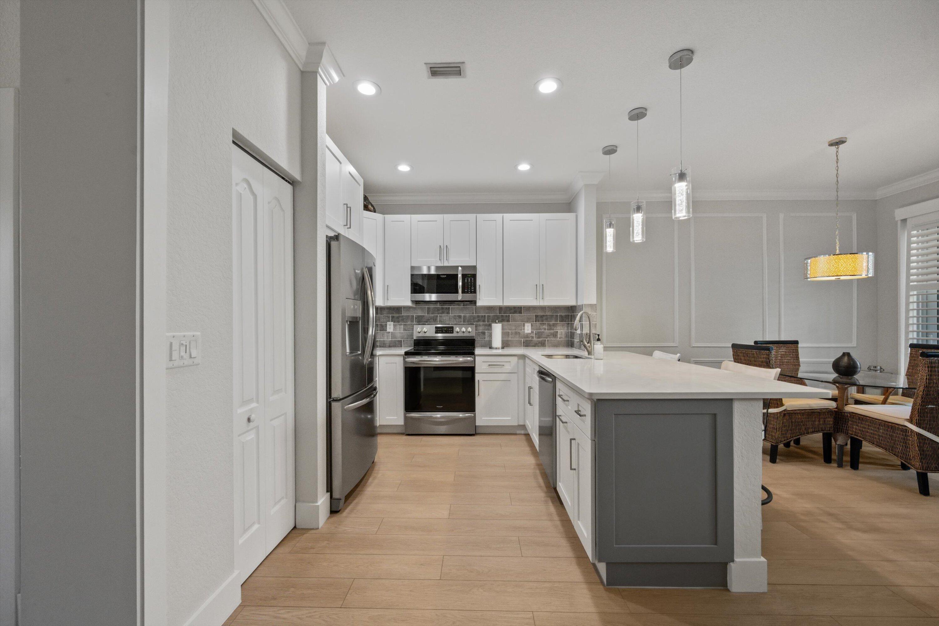 6058 Seminole Gardens Circle Riviera Beach, FL 33418 - Photo 8 of 47 a kitchen with a sink a counter top space stainless steel appliances and cabinets
