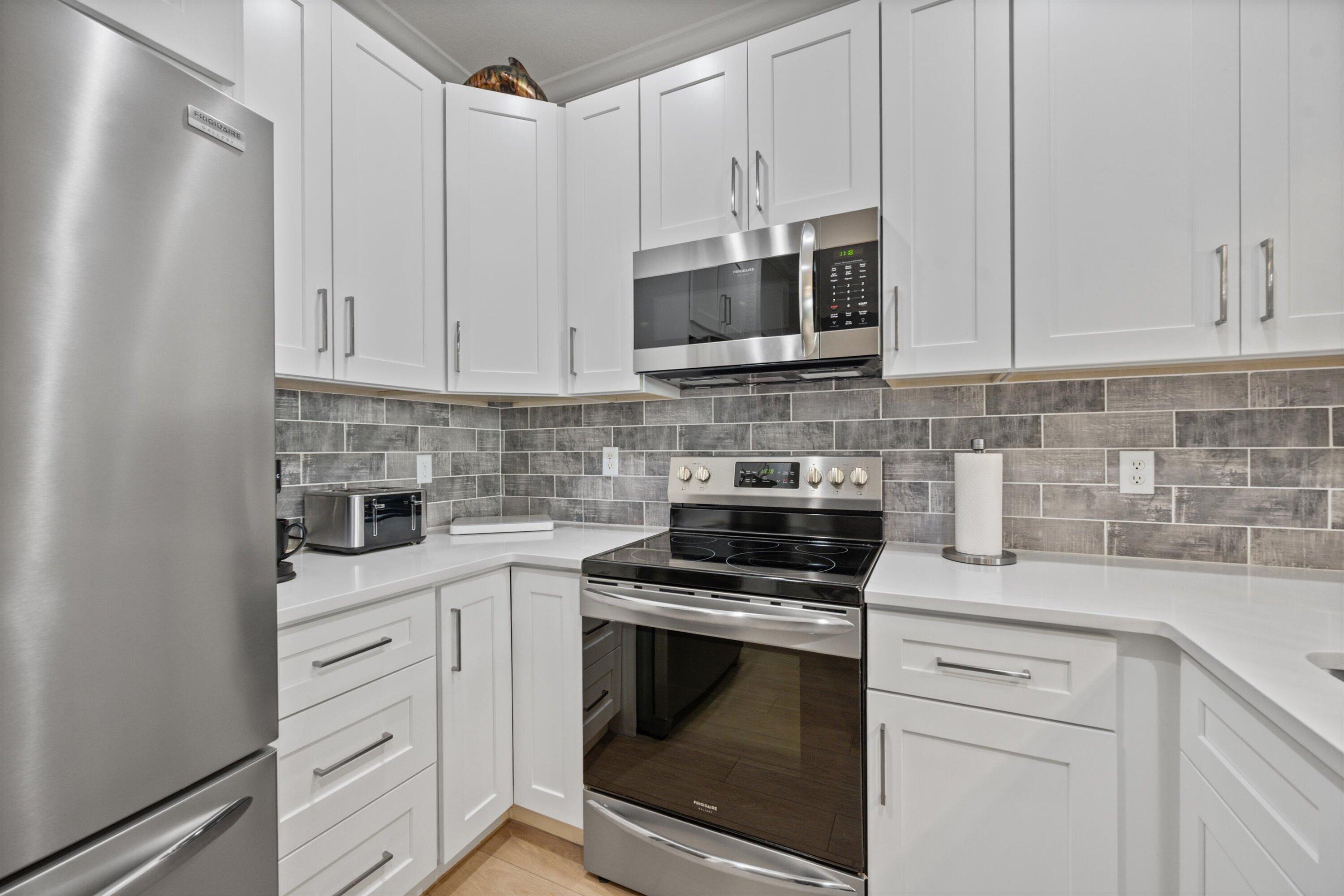 6058 Seminole Gardens Circle Riviera Beach, FL 33418 - Photo 10 of 47 a kitchen with white cabinets and stainless steel appliances