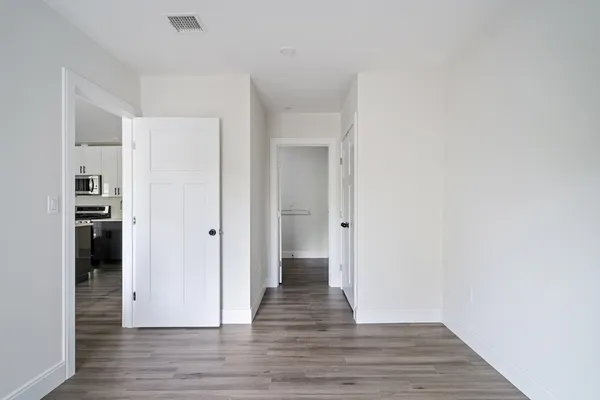 a view of an empty room with wooden floor and closet