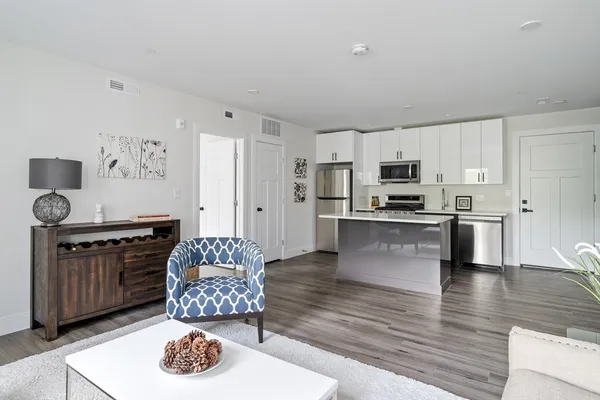 a kitchen with stainless steel appliances granite countertop a stove top oven a sink a dining table and chairs with wooden floor