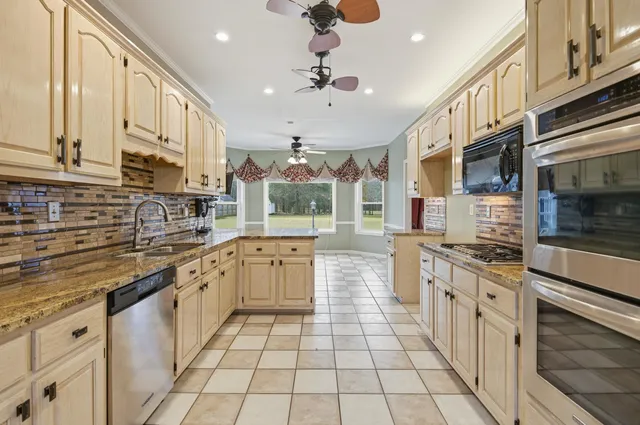 a kitchen with stainless steel appliances granite countertop a stove a sink and a refrigerator